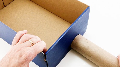 A shoebox that is about 3 tiome as heigh as a cardboard tube.