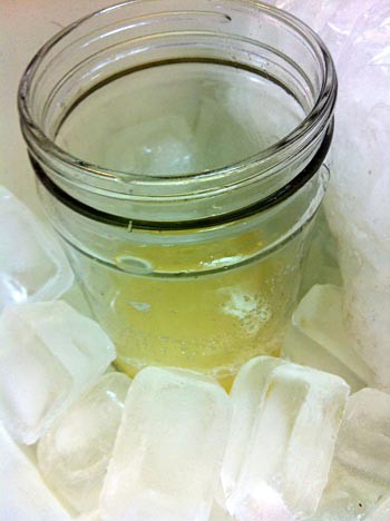 A glass jar holding a yellow catalase solution is put in a container filled with ice