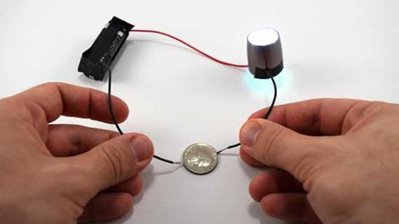 A simple circuit with a coin closing the connection, part of an activity to explore conductors and insulators