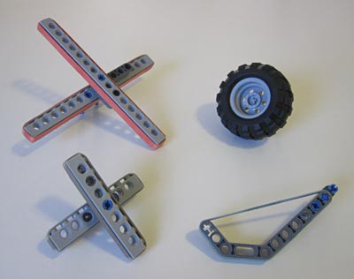 Various Lego attachments wrapped in rubber bands next to a rubber Lego wheel