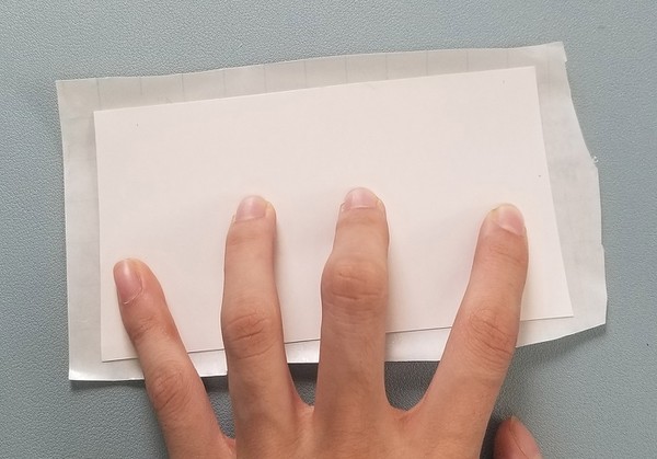 Demonstration of how the glossy temporary tattoo backing paper is smaller than the Con-Tact paper. 