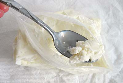 Spoon scoping white ice cream from a plastic bag