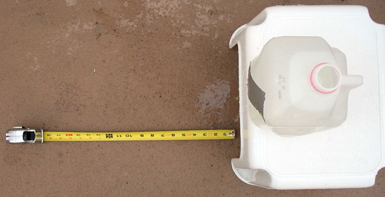 Top-down photo of a milk jug filled with water on top of a plastic stool