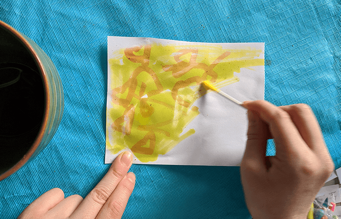Turmeric being painted onto a message that has been written with an invisible ink