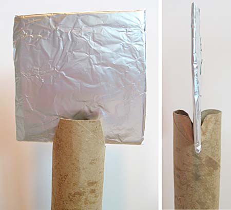 A cardboard square is wrapped in a layer of aluminum foil and is inserted into slits at the end of a cardboard tube
