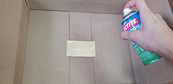 Spraying adhesive 12-15 inches away from vinyl tattoo sheet and one layer of metal leaf. 