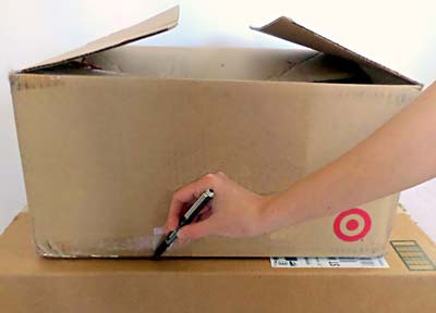 The outline of a smaller cardboard box is traced on the lid of a larger cardboard box