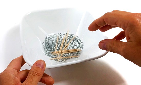 A bowl filled with paper clips and toothpicks. 