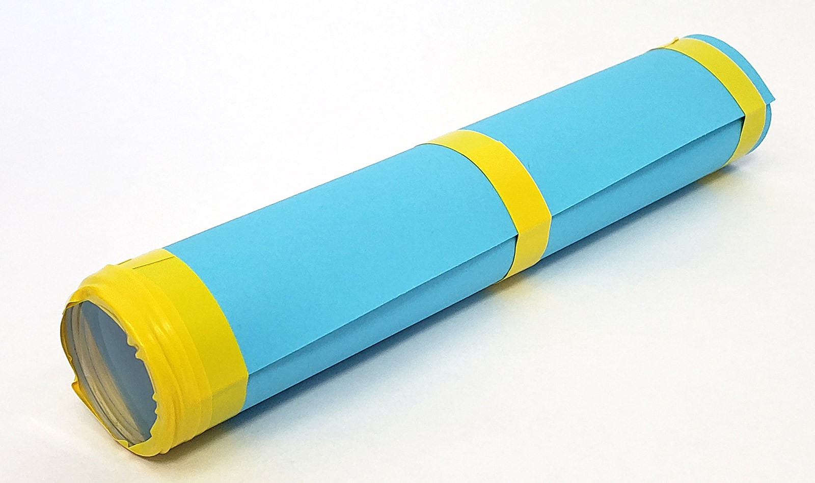 Cardstock tube with a lens taped to one end and additional pieces of tape holding the tube shape in place.