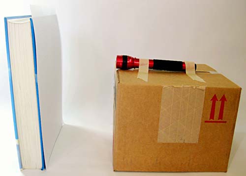 Sheet of graph paper taped to a text book in front of a flashlight on a box