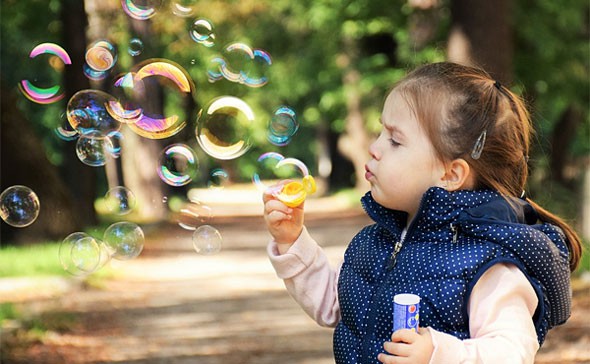 A small child creates bubbles using a bubble wand