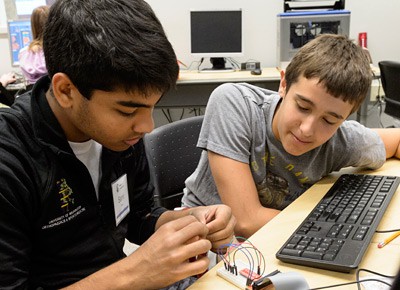 Two students connect jumper wires on a breadboard