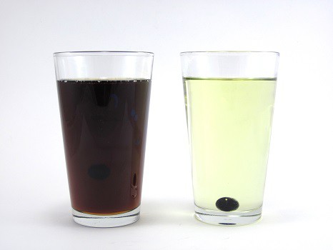 Two marbles going down two glasses containing liquids with different viscosity.