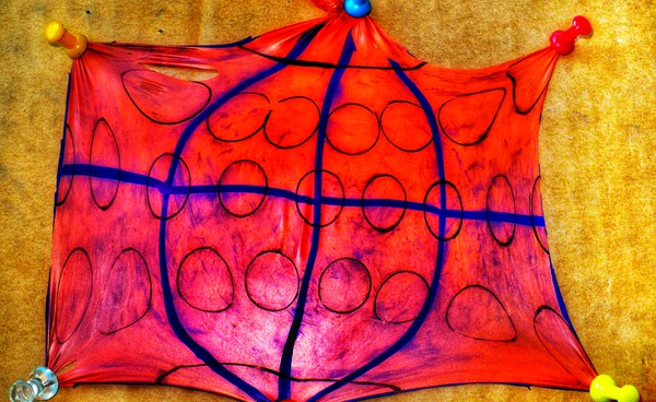An orange balloon map stretched out with circles and latitude/longitude lines drawn on it.