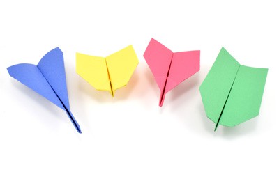 Four different paper airplane designs made from colored construction paper.