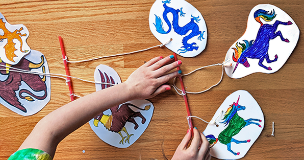 Kid attaching colorful drawings to an art mobile