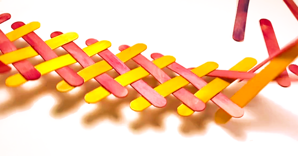 Red and yellow wooden sticks interwoven to create a chain reaction when released