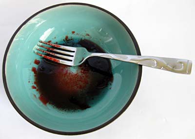 Dark red liquid is mixed in a bowl with a fork