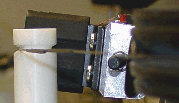 A teflon cylinder between two wheels adds tension to the wire running across them