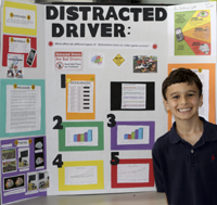 Student Andrew Lee with distracted driving project display board