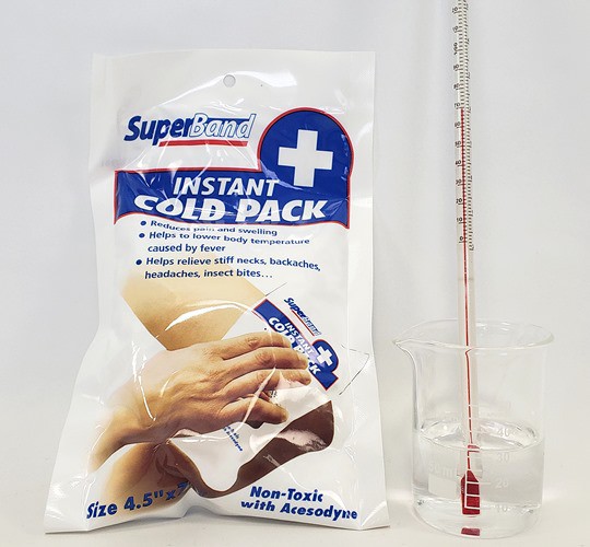 An instant cold pack next to a beaker with a thermometer in it.