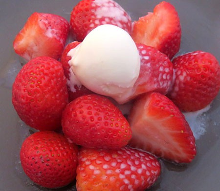 A small scoop of ice cream placed on a pile of strawberries