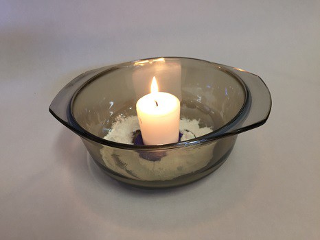 A lit candle and baking soda in a glass baking dish