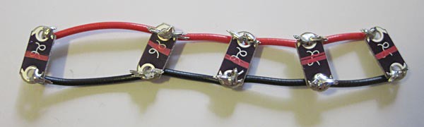 Four red wires and four black wires are soldered to the positive and negative terminals of five LEDs