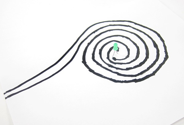Two black lines painted in a spiral and connected by an LED at the center of the spiral