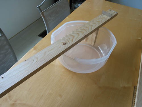 A plastic container holds wooden plank as a wooden support is glued underneath