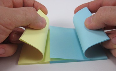 A blue and yellow paper pad have their pages interlaced one by one