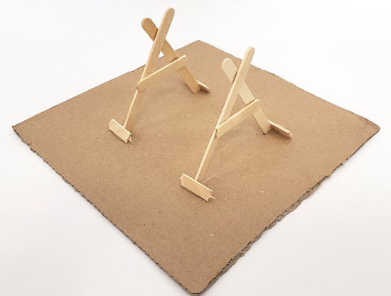 Two A-frame pieces standing vertically on a piece of cardboard, parallel to each other a few inches apart.