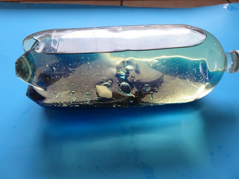 A liter bottle filled with oil and blue water