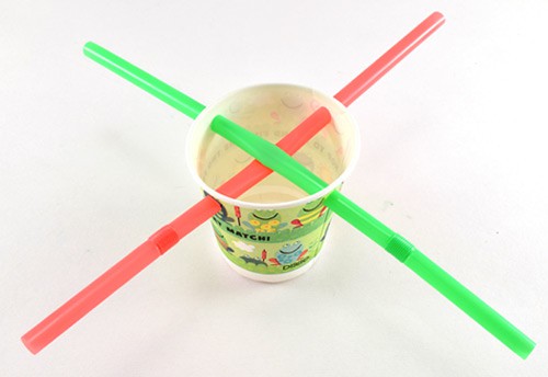 Four holes are punched through the rim of a paper cup and two straws are inserted perpendicular to each other