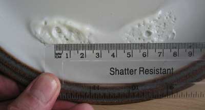 A ruler is used to measure the distance between cooked portions of egg whites on a plate