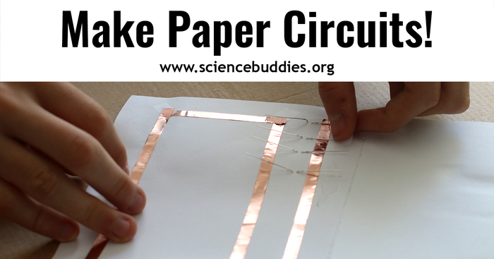 Hands pressing copper tape and LEDs in place in a paper circuit