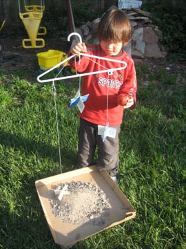 A child holds a clothes hanger with three homemade stardust catchers hanging from it