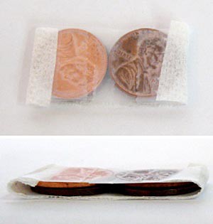 A small strip of paper towel wraps around two stacks of pennies covered in tape