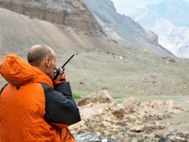 Man in a rugged landscape talking on a satellite phone