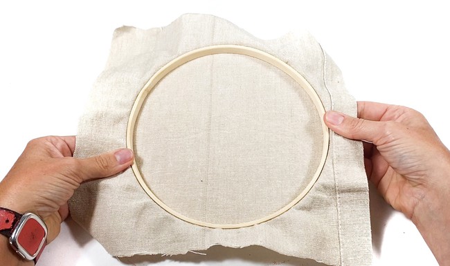 A wooden embroidery hoop with canvas inside. 