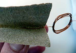 Sandpaper is used to remove all of the insulation from a single axle of a coiled wire