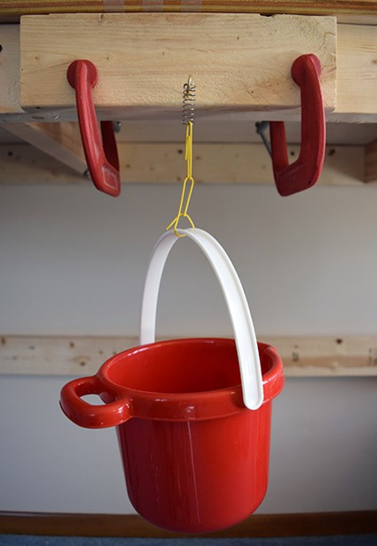 A spring attached to a hook has a plastic pail suspended from it