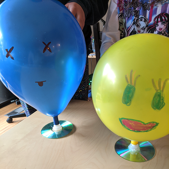 Two hovercrafts made from balloons, bottle pop-tops and CDs