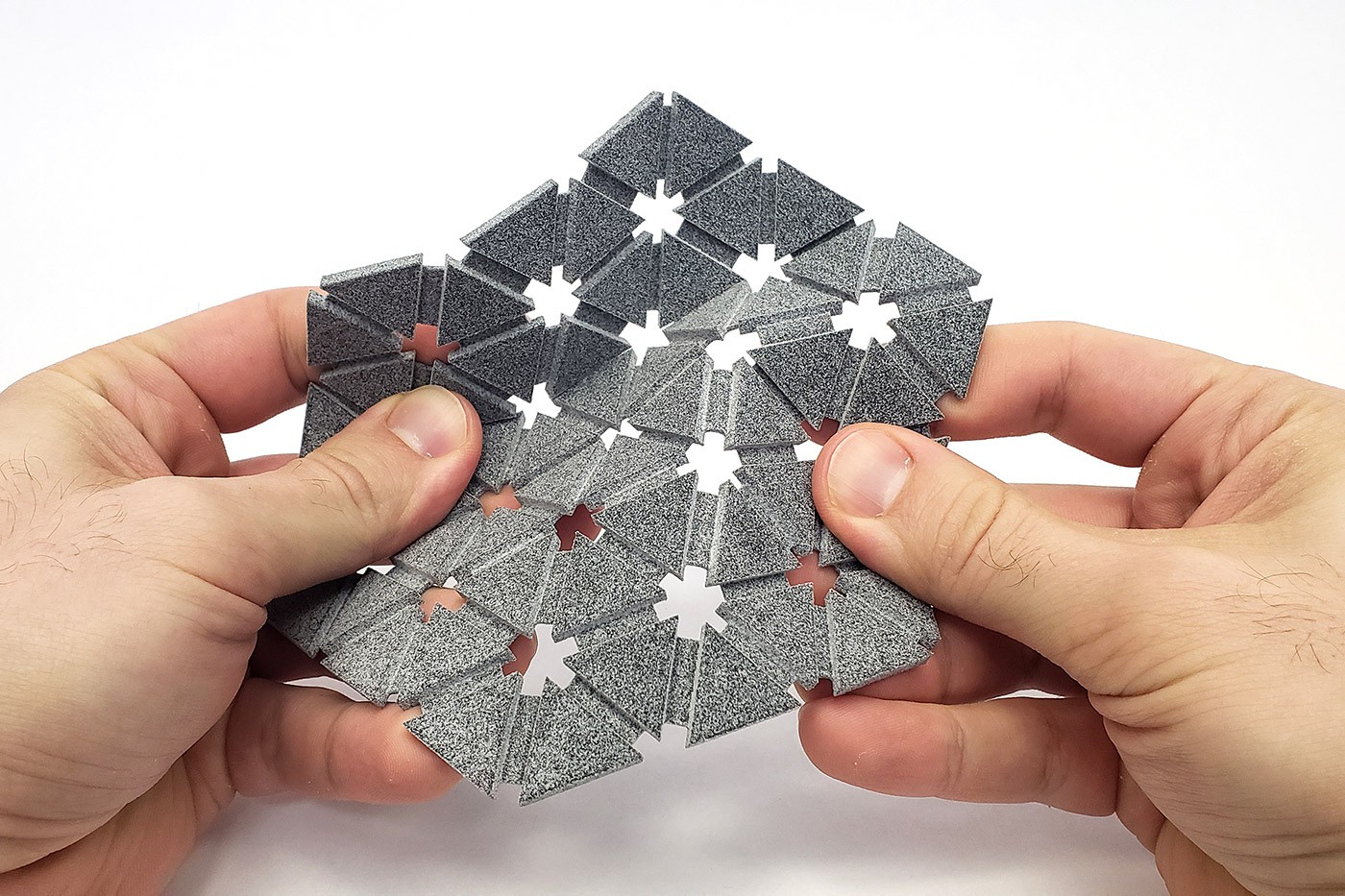 Two hands hold a piece of 3D printed fabric.