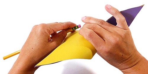 Hands holding a paper pinwheel. The paper pinwheel is attached to the pencil eraser with a thumbtack. 