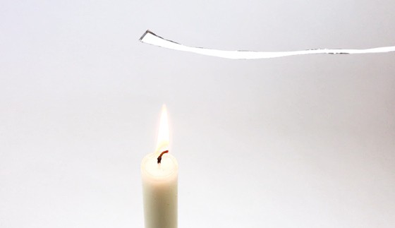 Paper-aluminum strip held about 2 inches above a candle flame with the aluminum side facing down.