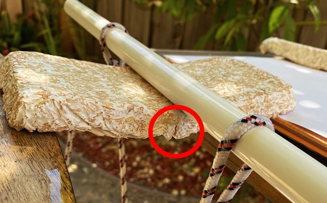 Mycelium composite panel bridging the gap between two tables. A dowel lays across on the panel.  