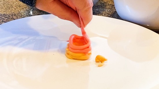 A second layer of red icing being placed on  tower of two layers of yellow icing.   