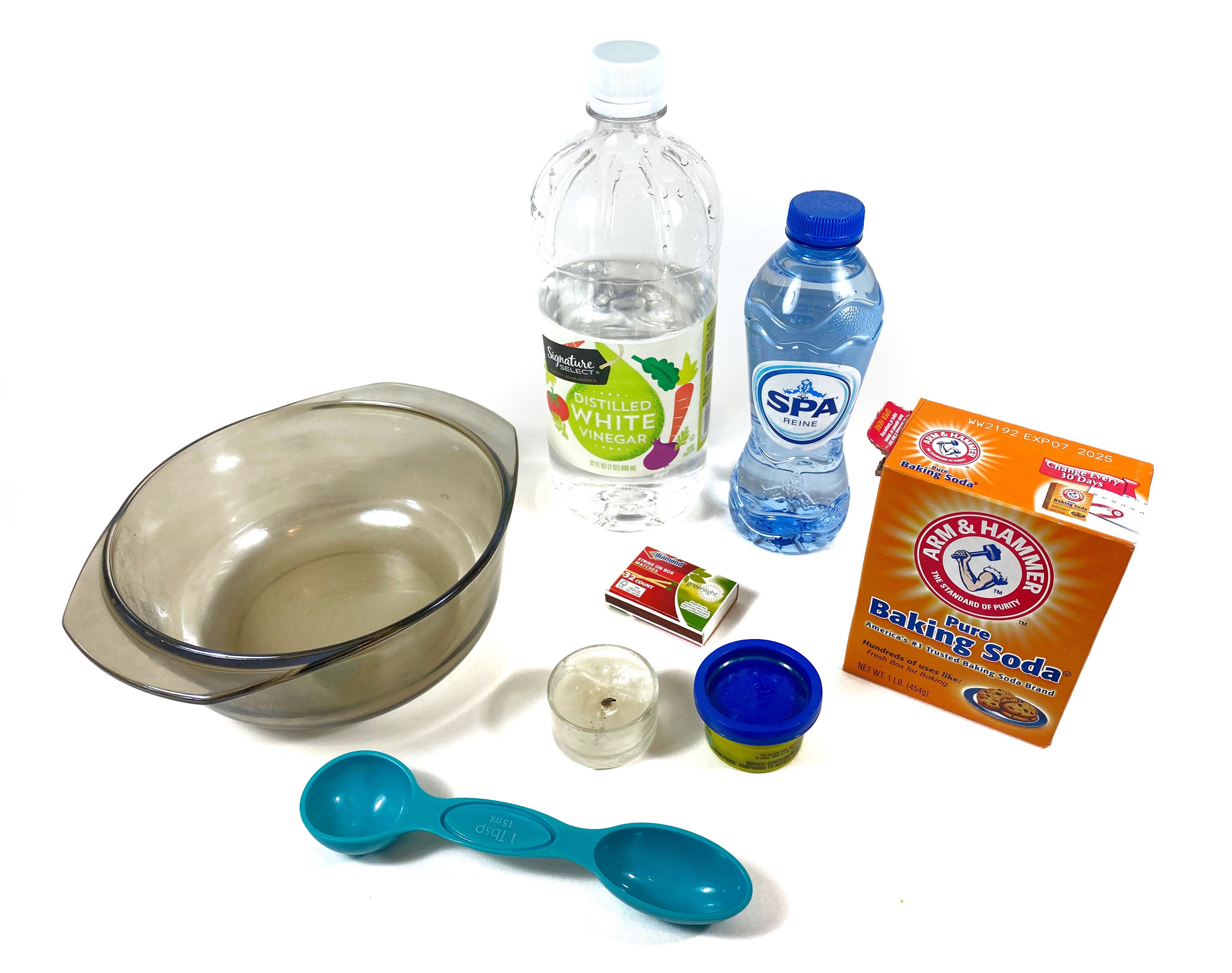 The image shows a glass bowl, a measuring spoon, a candle, some Play-Dough, a matchbox, a baking soda container, a bottle of water, and a bottle of white vinegar.