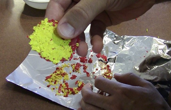 The crayon sedimentary rock removed from the aluminum foil. The two colors of crayon shavings form two mostly distinct layers.